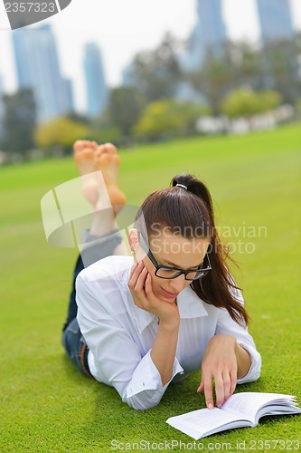 Image of Young woman reading a book in the park