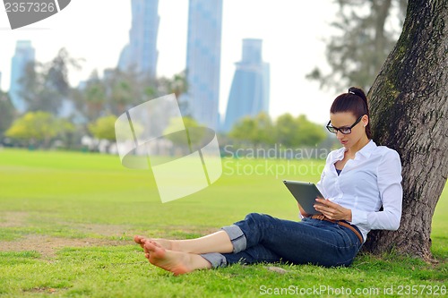 Image of Beautiful young woman with  tablet in park