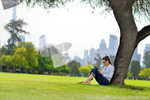 Image of Beautiful young woman with  tablet in park