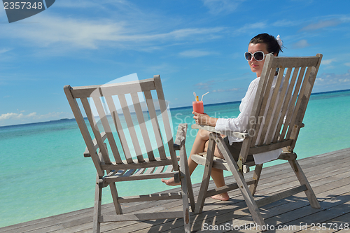 Image of Beautiful young woman with a drink by the sea