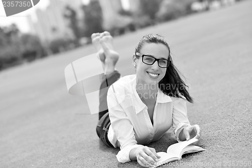 Image of Young woman reading a book in the park