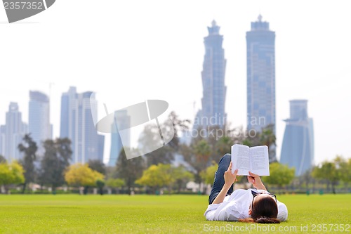 Image of Young woman reading a book in the park
