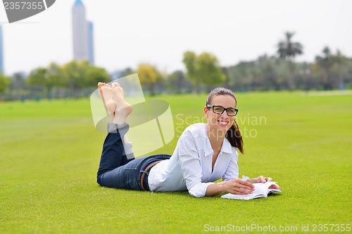 Image of Young woman reading a book in the park