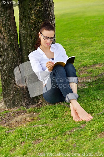 Image of Young woman reading a book in the park