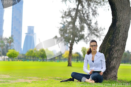 Image of Beautiful young woman with  tablet in park