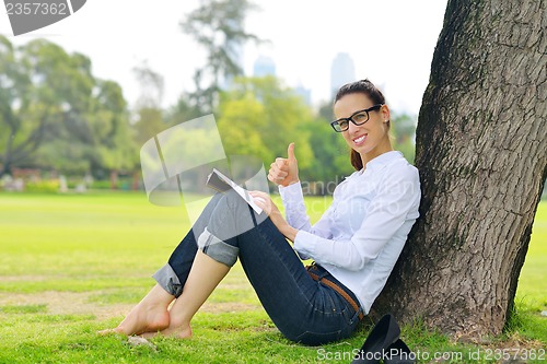 Image of Young woman reading a book in the park