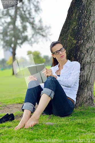 Image of Beautiful young woman with  tablet in park