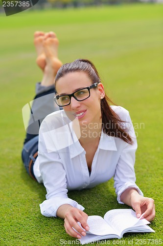 Image of Young woman reading a book in the park
