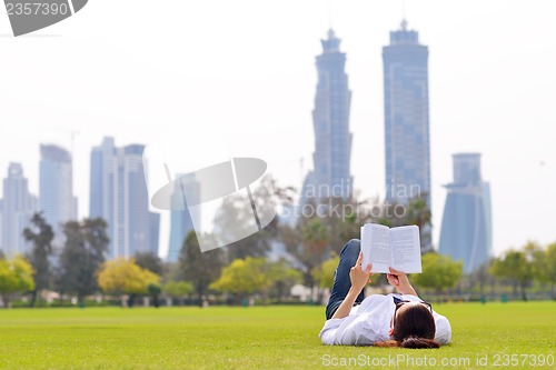 Image of Young woman reading a book in the park