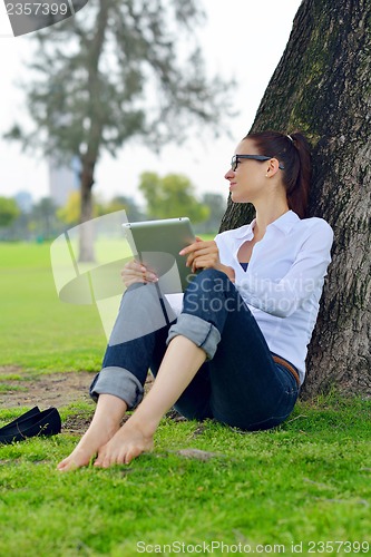 Image of Beautiful young woman with  tablet in park