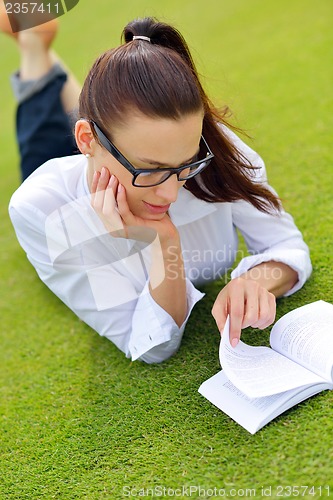 Image of Young woman reading a book in the park