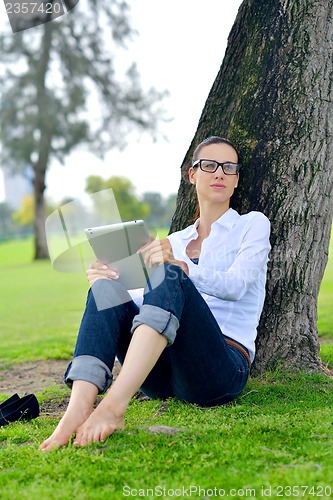 Image of Beautiful young woman with  tablet in park