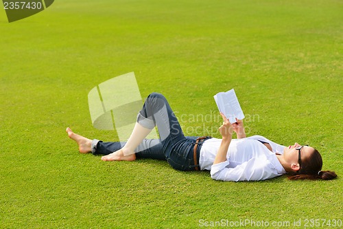 Image of Young woman reading a book in the park