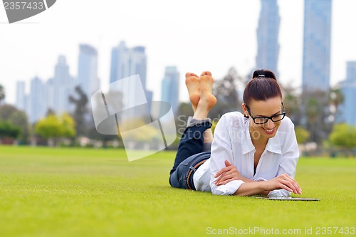 Image of Beautiful young woman with  tablet in park