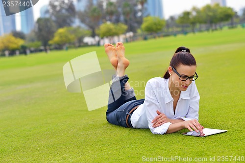 Image of Beautiful young woman with  tablet in park