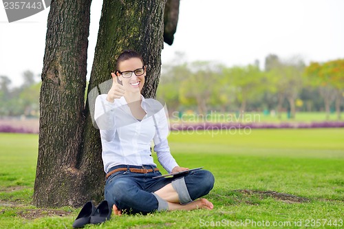 Image of Beautiful young woman with  tablet in park