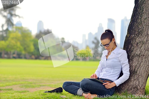 Image of Beautiful young woman with  tablet in park