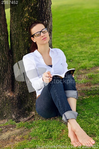 Image of Young woman reading a book in the park