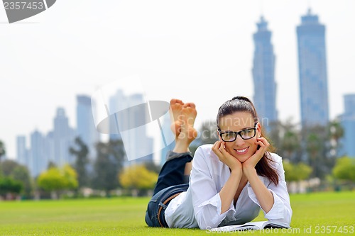 Image of Young woman reading a book in the park