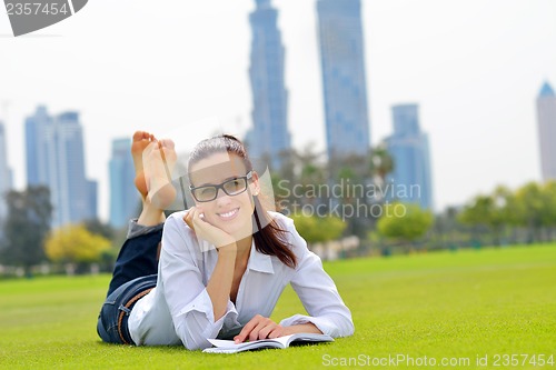 Image of Young woman reading a book in the park