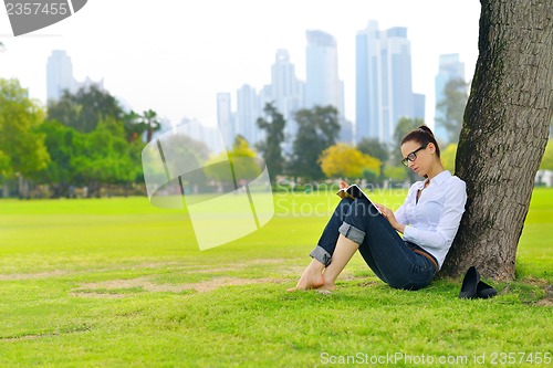 Image of Young woman reading a book in the park