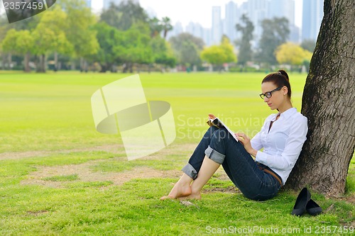 Image of Young woman reading a book in the park