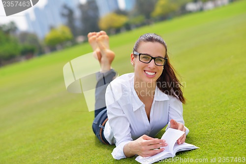 Image of Young woman reading a book in the park