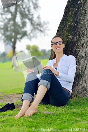 Image of Beautiful young woman with  tablet in park