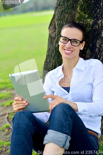 Image of Beautiful young woman with  tablet in park