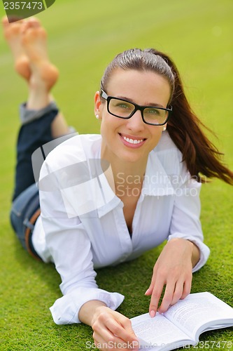Image of Young woman reading a book in the park