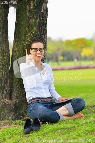 Image of Beautiful young woman with  tablet in park
