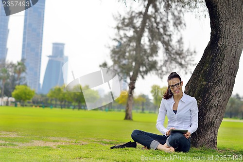 Image of Beautiful young woman with  tablet in park