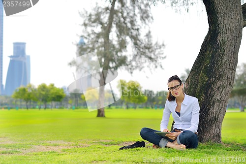 Image of Beautiful young woman with  tablet in park