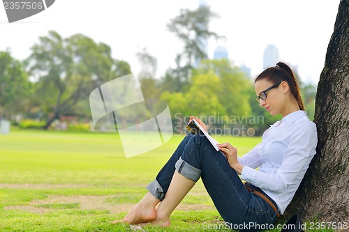 Image of Young woman reading a book in the park