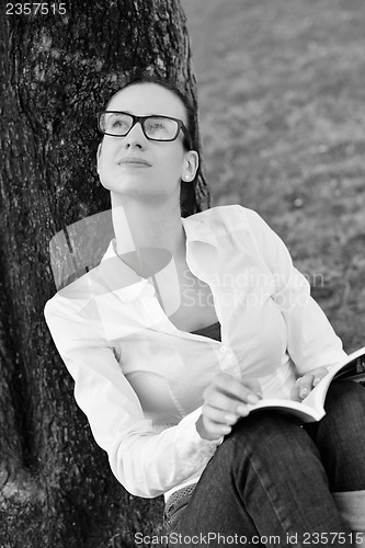 Image of Young woman reading a book in the park