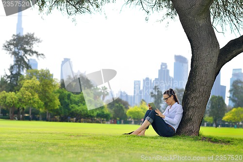Image of Beautiful young woman with  tablet in park