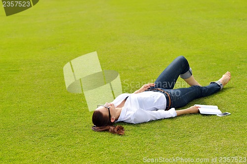 Image of Young woman reading a book in the park