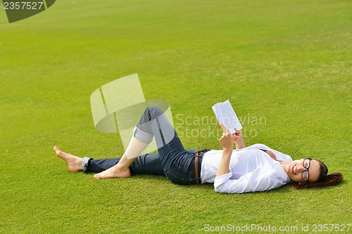 Image of Young woman reading a book in the park