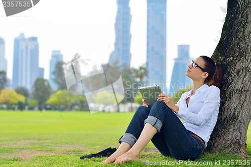 Image of Beautiful young woman with  tablet in park