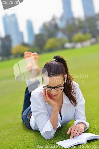 Image of Young woman reading a book in the park