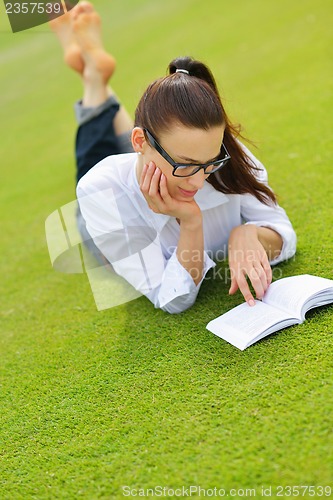 Image of Young woman reading a book in the park