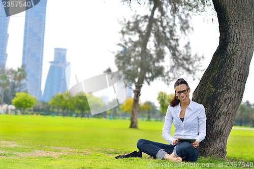 Image of Beautiful young woman with  tablet in park