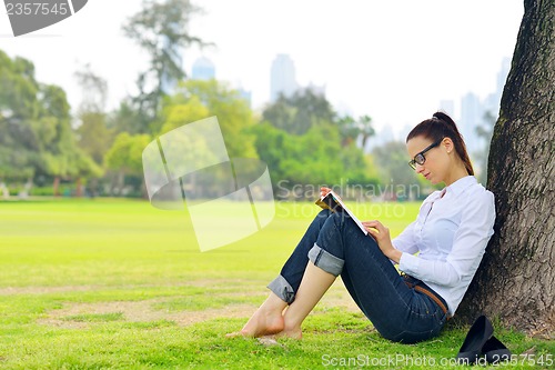 Image of Young woman reading a book in the park
