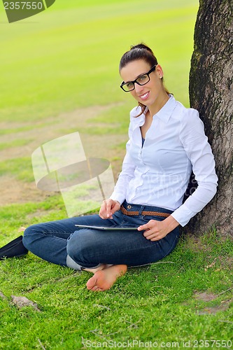 Image of Beautiful young woman with  tablet in park