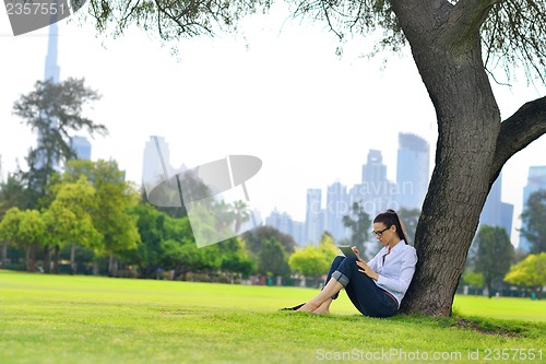 Image of Beautiful young woman with  tablet in park