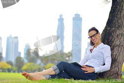 Image of Beautiful young woman with  tablet in park