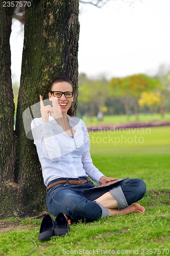 Image of Beautiful young woman with  tablet in park