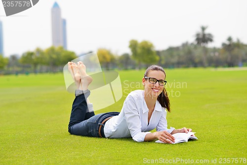 Image of Young woman reading a book in the park