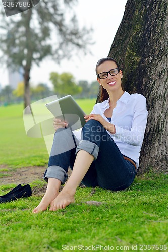 Image of Beautiful young woman with  tablet in park