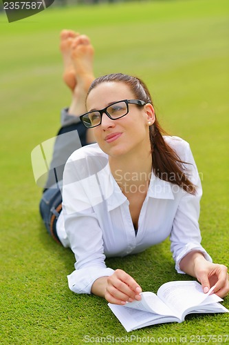 Image of Young woman reading a book in the park